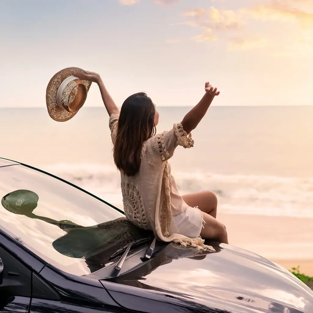 A lady on top of a rental car celebrating